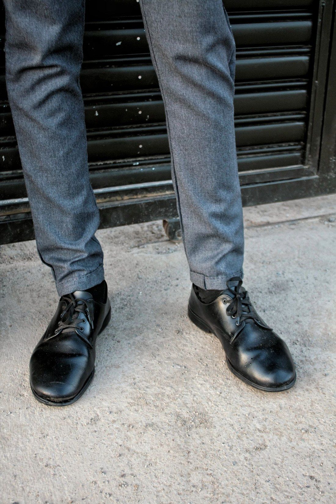 Graue Stoffhose mit umgeschlagenem Saum über schwarzen Lederschuhen